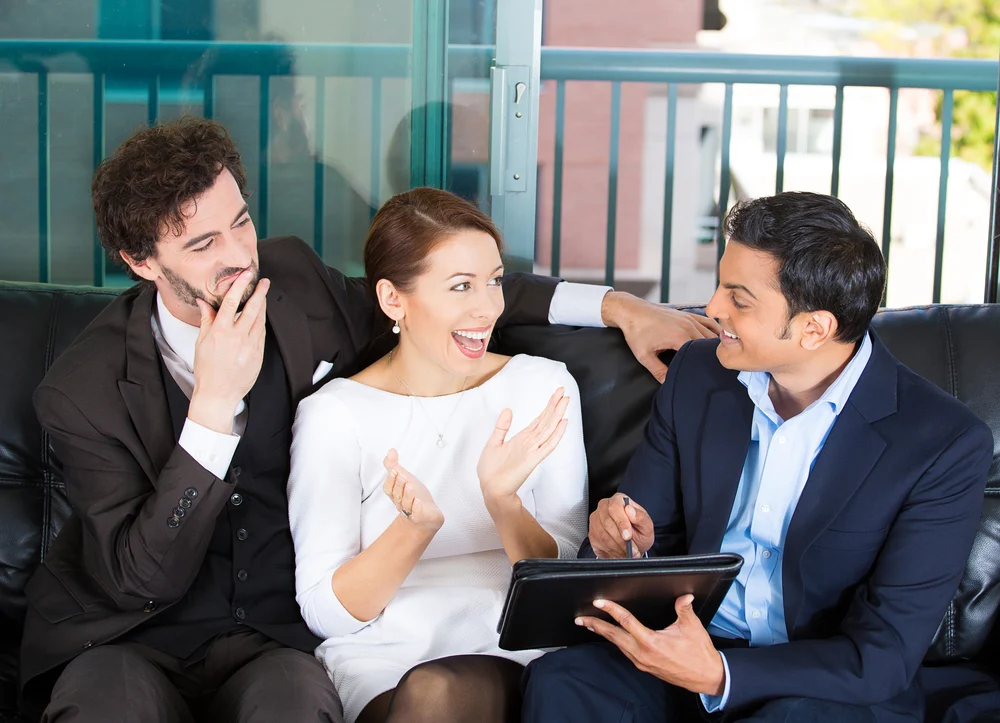 Picture of a manager, financial consultant, banker presenting to young smiling married couple, business investment opportunity plan, isolated on background of city buildings